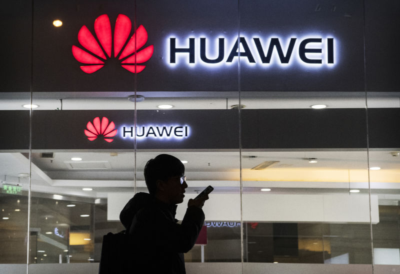 A man speaks on a smartphone outside a Huawei storefront.